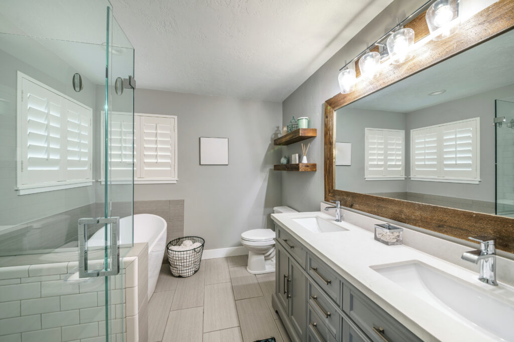 Modern bathroom with twin sinks, tub, and glass shower