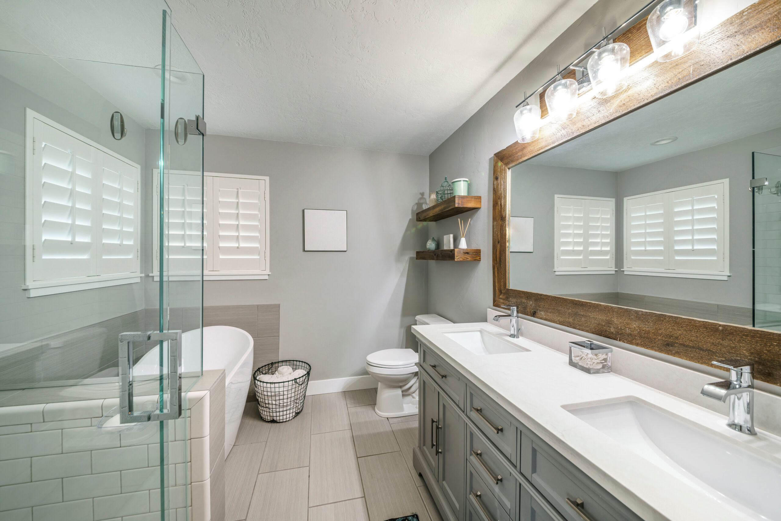 Modern bathroom with twin sinks, tub, and glass shower